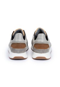 Szare zamszowe sneakersy z gładką, szaro skórzaną piętą, brązowymi gumowymi akcentami i białą podeszwą. Zawierają wytłoczoną nazwę marki na pięcie.