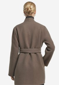 Brun ullkappa med bälte i midjan, hög krage och långa ärmar, med en mjuk textur och rak passform.