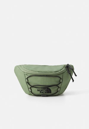 Geantă de talie din material verde, cu buzunar cu fermoar, curele ajustabile și logo negru. Prezintă o suprafață texturată și un design cu cordon elastic pe față.