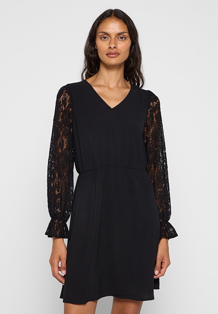 Schwarzes Kleid mit langen Spitzenärmeln, V-Ausschnitt und ausgestellten Manschetten; weicher Stoff und elastischer Bund für einen bequemen Sitz.