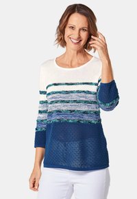 Der Strickpullover hat ein gestreiftes Design in Weiß, Blau und Grün, mit Dreiviertelärmeln und einem strukturierten, gewebten Muster.