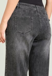 Vaqueros de mezclilla gris de talle alto con una textura suave, que cuentan con dos bolsillos traseros y detalles de costura. Complementan atuendos casuales o relajados.