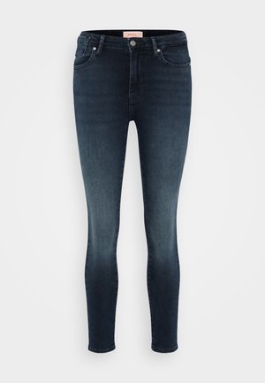 Tmavomodré úzke džiny vyrobené z denimu, s klasickým dizajnom piatich vreciek, zapínaním na gombík a minimálnym vyblednutím.