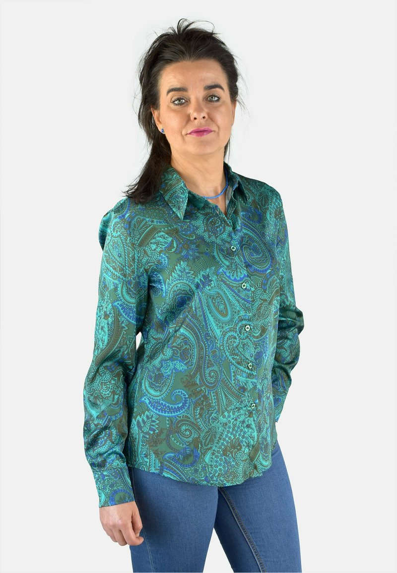 Camisa de botón de patrón paisley en verde y azul con cuello; fabricada en tejido suave, de mangas largas y con botones en la parte delantera; combinada con jeans azules.
