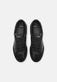 Svarta sneakers med en blandning av slätt läder och mocka, med runda snören, en logo på tungan och en vadderad sula.