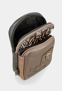 Mehrere Taschen mit Reißverschluss in schwarzem und braunem Kunstleder. Mit einem dekorativen Patch und gedrucktem Text auf der Oberfläche, innere Muster sichtbar.