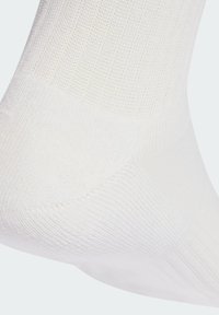 Calcetín blanco de algodón con un patrón acanalado texturizado, que presenta talón y punta reforzados. El diseño es sin costuras y ligero.