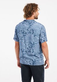 Korte mouw blouse in het blauw, met een bloemen- en bladenpatroon. Gemaakt van lichte stof, met een relaxte pasvorm en achterste schouderdeel details.
