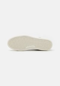 Suela de zapatilla blanca con un patrón texturizado en forma de panal. Presenta un prominente logotipo de Levi's y bordes redondeados para un diseño suave.