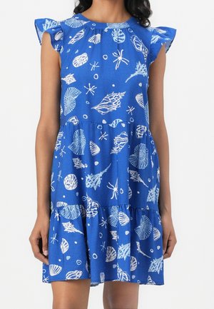 Sininen hihaton mekko, jossa valkoisia simpukka- ja meritähdkuvioita, röyhelöiset hihansuut ja kerroksellinen hame.