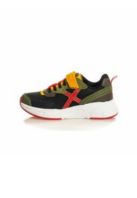 Zapatilla negra y verde con una suela blanca, acentos rojos, cordones amarillos y rojos, una correa de velcro y detalles texturizados en la parte trasera.