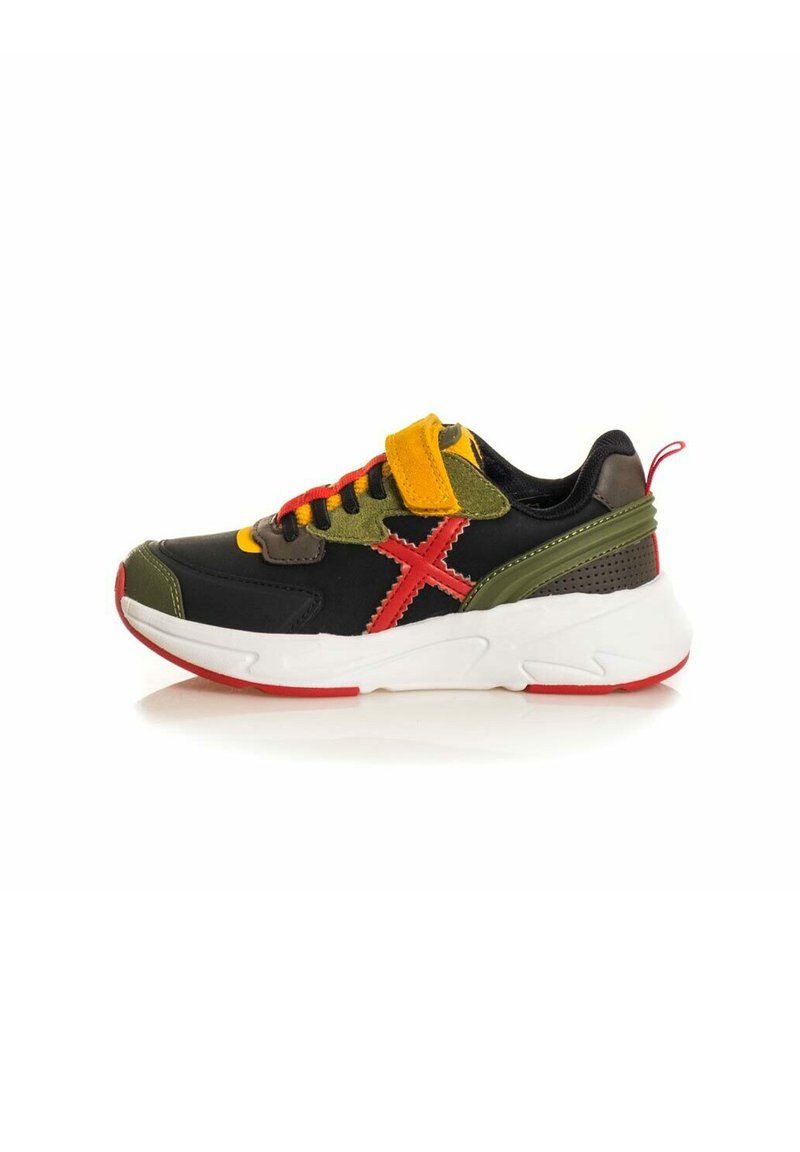 Zapatilla negra y verde con una suela blanca, acentos rojos, cordones amarillos y rojos, una correa de velcro y detalles texturizados en la parte trasera.