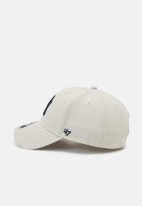 Casquette de baseball blanche avec une visière courbée, ornée d'un logo brodé marine et d'accents sombres. Fabriquée en tissu texturé avec des trous de ventilation.