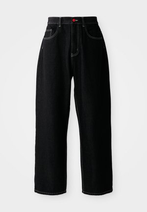 Sorte vide bukser laget av denim, med hvite sømmer, fem-lomme design og en rød knapp i livet.