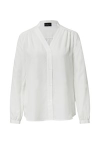 Blouse blanche à manches longues avec un décolleté en V, dotée d'une fermeture à boutons et d'accents plissés aux épaules. Fabriquée en tissu léger et lisse.