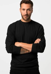 Schwarzes Langarm-T-Shirt mit rundem Ausschnitt und Slim-Fit. Mit einem dezenten Markenlogo auf der Brust. Sanfte Stofftextur.