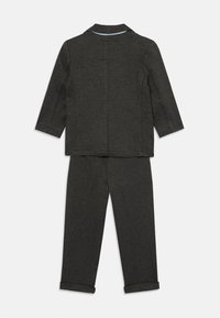 Graues zweiteiliges Anzugset, bestehend aus einer Jacke mit Kragen und einem hellblauen Akzent am Hals sowie passgenauen Hosen mit aufgerolltem Saum.