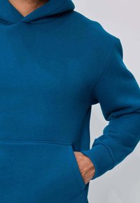 Sweat à capuche en polaire bleu avec une poche frontale, des poignets côtelés et une capuche à cordon. Texture lisse et design simple et épuré.