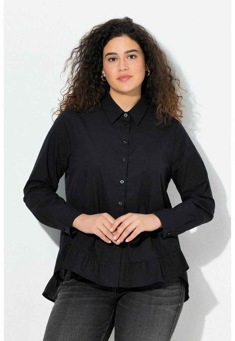 Black button-up shirt with long sleeves, ruffled hem, and a collar. Made from a smooth fabric, styled with a relaxed fit.