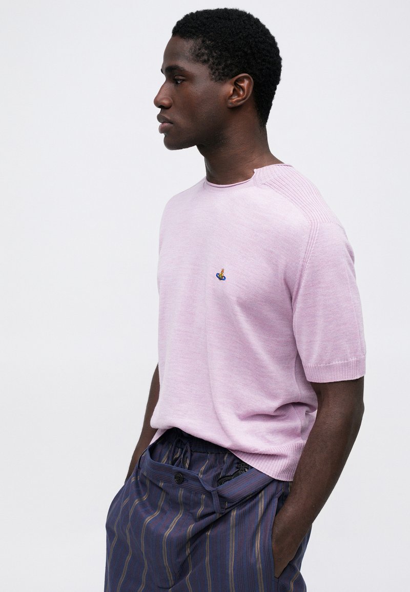 Maglioncino corto a maniche corte di colore rosa chiaro, con scollatura rotonda e dettagli testurizzati sulle spalle, caratterizzato da un piccolo logo ricamato colorato.