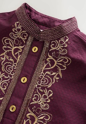 Kurta en tissu bordeaux avec broderies dorées le long du plastron et du col, ornée de boutons décoratifs et de motifs texturés.
