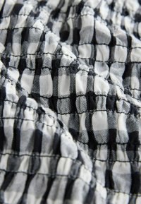 Mustvalge ruuduline kangas, millel on kortsus tekstuur, sisaldades vertikaalseid ja horisontaalseid jooni, mis moodustavad ruudustiku mustri.