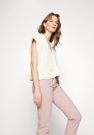 Top envolvente de manga curta com textura cremosa e decote em V, combinado com calças justas em rosa suave. Design simples e limpo.