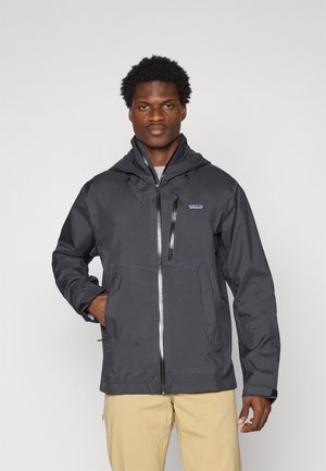 Veste à capuche noire en matériau léger et résistant à l'eau. Présente une fermeture éclair à l'avant, des cordons de serrage ajustables et des poches zippées.