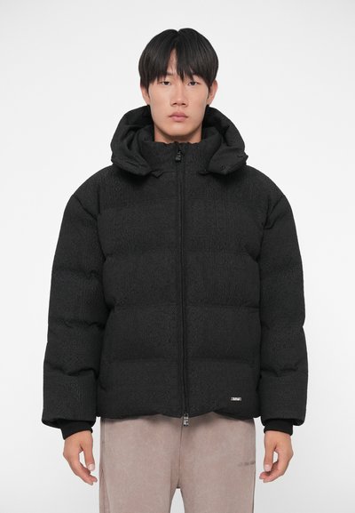 Black puffer jacket with a hood, featuring a quilted texture and a front zipper. Ribbed cuffs and a logo patch at the hem.