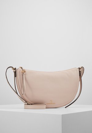 Beżowa skórzana torebka Michael Kors w kształcie półksiężyca na ramię, z regulowanym paskiem i złotymi okuciami, prezentowana na białym postumencie.