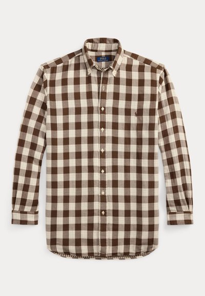 Camisa de botões com padrão xadrez em grandes quadrados castanhos e creme, gola com colarinho, mangas compridas e botões brancos. Logótipo discreto no peito.