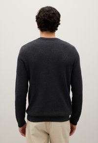 Maglione grigio scuro con lavorazione a maglia testurizzata, scollo a giro, maniche lunghe e orlo a coste, indossato su pantaloni chiari. Vista posteriore visualizzata.