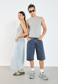 Grå ermeløse topper, lys blå denimskjørt og mørkeblå shorts. Fottøyet inkluderer sneakers med neon-detaljer og grå joggesko.