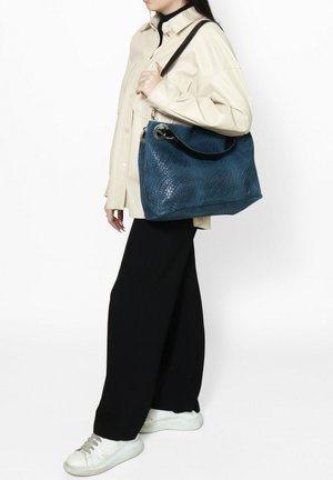 Borsa a tracolla in pelle intrecciata blu con una texture liscia, dotata di una tracolla nera e di un accento metallico circolare. La borsa è grande e morbidamente sagomata.