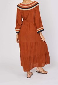 Maxi dress in burnt orange fabric, featuring a gathered waist, three-quarter sleeves, and embroidered accents on the neckline and cuffs.