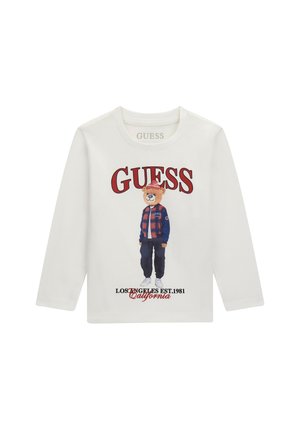 Chemise blanche à manches longues avec le texte "GUESS", illustration d'un ours portant une veste à carreaux et un chapeau, et texte "LOS ANGELES EST. 1981 California".