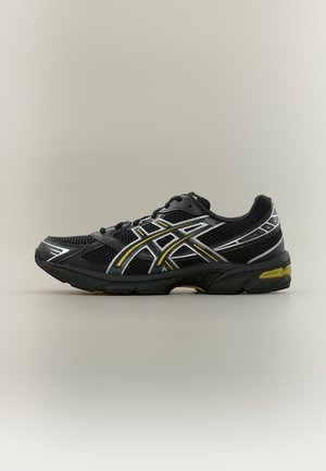 Chaussure de course athlétique noire avec une tige en mesh, des bandes jaunes et blanches sur les côtés, et une semelle amortie avec des accents jaunes, vue de côté.