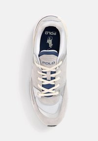 Sneakers Polo s šedým semišovým svrškem a síťovinovými detaily, krémovými tkaničkami a tmavě modrou stélkou. Obsahuje logo vytištěné na jazyku.