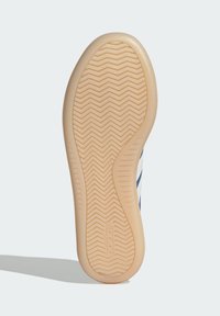 Gumeni potplat cipele s uzorkom riblje kosti, bež boje, sa ugraviranim logotipom i glatkom teksturom.