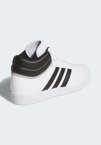Sneakers typu high-top z białą skórzaną cholewką, trzema czarnymi paskami, czarnym wyściełanym kołnierzem i teksturowaną białą gumową podeszwą.
