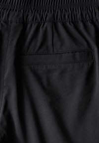 Zwarte broek met een elastische tailleband, een gladde stoffen textuur en een enkele achterzak met gestikte details.