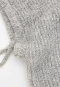 Țesătură tricotată gri, cu un model texturat, având fibre moi și pufoase și un detaliu cu șnur închis pe o latură.