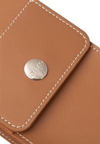 Brun læderpunge med hvid syning, der har et rundt sølvknapluk med embossing af "RYLKO." Glat tekstur, rektangulær form.