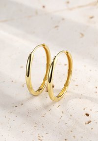 Goldfarbene, hohlgeformte Ohrringe mit glatter, polierter Oberfläche; kreisförmiges Design mit leicht ovaler Form; leicht und glänzende Oberfläche.