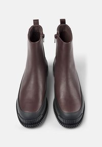 Bruna läderankelstövlar med elastiska sidopaneler och en texturerad svart gummisåle. Har dragkedjor för enkel på- och avtagning. Slät textur överlag.