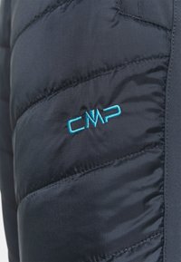 Padded tumma laivastonsininen takkiosa, jossa on viistotommot ja vaaleansininen brodeerattu CMP-logo kankaassa.