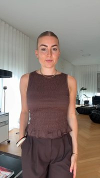 Braunes, gerafftes Tanktop mit einem Rüschensaum, kombiniert mit lockeren braunen Hosen. Glatte Stofftextur mit dezenten Raffungselementen.