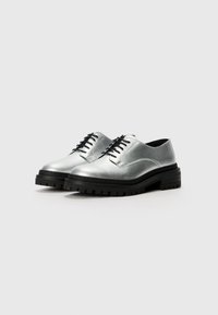 Zilveren leren schoenen met een glanzende afwerking, zwarte veters en een stevige zwarte zool met een getande textuur. Klassiek oxford ontwerp.