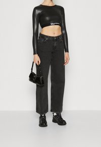 Musta lyhythihainen cropped-paita, korkeavyötäröiset mustat leveät farkut ja mustat tennarit. Pieni musta käsilaukku, jossa on kantohihna.