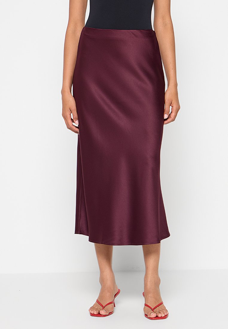 Bourgondische satijnen midi-rok met een gladde textuur, voorzien van een zijsplijt en een rechte silhouet. Gecombineerd met rode sandalen.